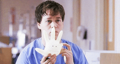 Man In Blue Scrub Holding Smiley Face Glove GIF