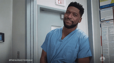 Man In Blue Scrub Leaning Against Exit Sign GIF