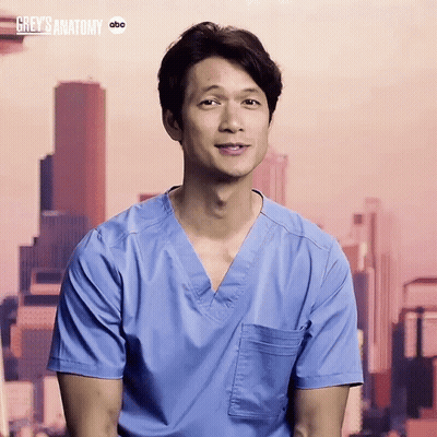Man In Blue Scrub Smiling In Front Of Grey's Anatomy Sign GIF