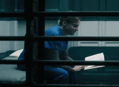 Man In Blue Scrub Top Reading Book On Couch GIF