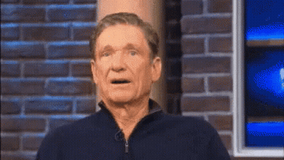 Man In Blue Shirt Against Brick Wall GIF
