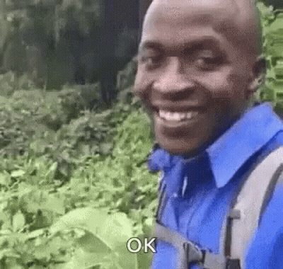 Man In Blue Shirt And Backpack Smiling GIF