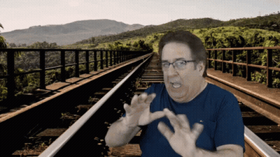 Man In Blue Shirt And Glasses On Train Tracks GIF