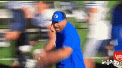 Man In Blue Shirt And Hat Talking On Cell Phone In Field GIF