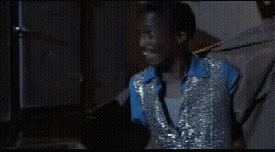 Man In Blue Shirt And Silver Vest Smiles GIF