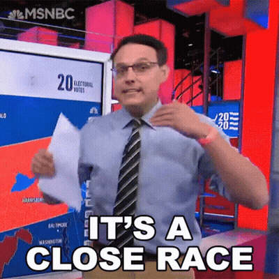 Man In Blue Shirt And Tie Holding Paper Saying It's A Close Race GIF