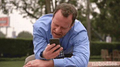 Man In Blue Shirt And Tie Looking At Phone GIF