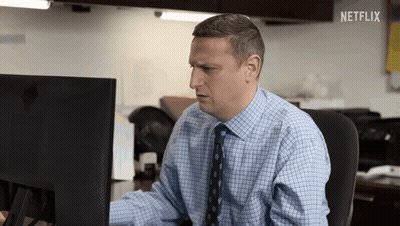 Man In Blue Shirt And Tie Sitting In Front Of Netflix Sign GIF