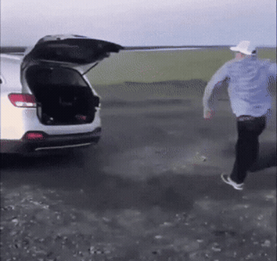 Man In Blue Shirt And White Hat Running To Car With Open Trunk GIF