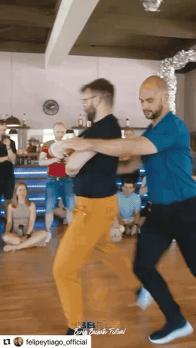 Man In Blue Shirt Dancing With Man In Orange Pants GIF
