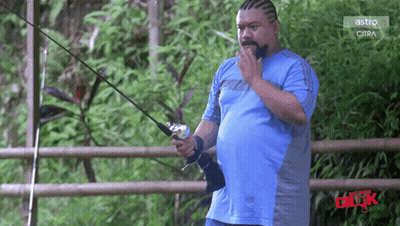 Man In Blue Shirt Holding Fishing Rod In Front Of Astro Fence GIF