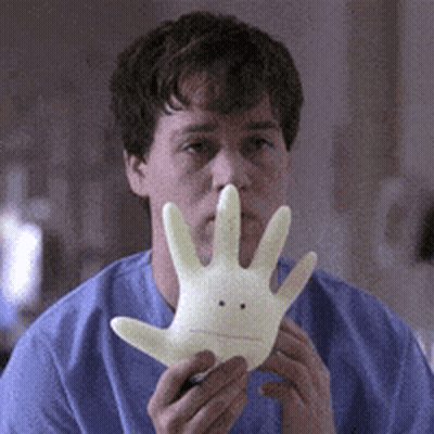 Man In Blue Shirt Holding Glove With Face GIF