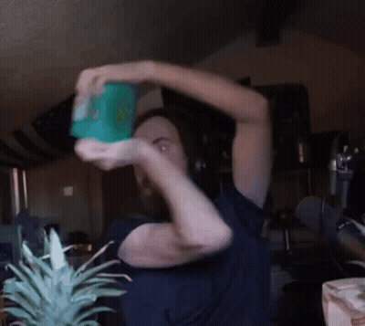 Man In Blue Shirt Holding Green Container With Cartoon Character GIF