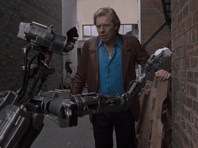 Man In Blue Shirt Holding Robotic Arm GIF