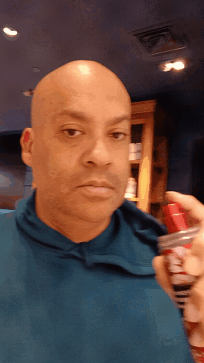 Man in Blue Shirt Holding Shaving Cream Spray Bottle