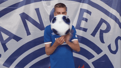 Man In Blue Shirt Holding Soccer Ball In Front Of Rangers Logo GIF