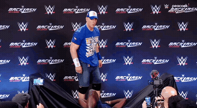 Man In Blue Shirt In Front Of Backlash Wall GIF