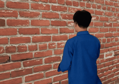 Man In Blue Shirt In Front Of Brick Wall GIF