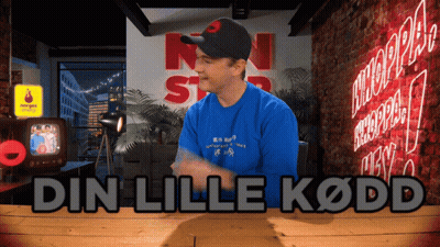 Man In Blue Shirt In Front Of Din Lille Kodd Sign GIF