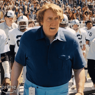 Man In Blue Shirt In Front Of Football Players With Letter C GIF