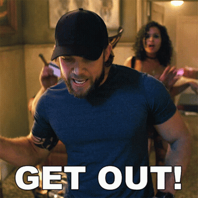 Man In Blue Shirt In Front Of Get Out Sign GIF