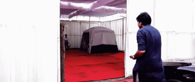 Man In Blue Shirt In Front Of Tent GIF