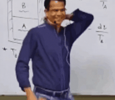 Man in Blue Shirt in Front of Whiteboard With Formula