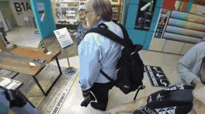 Man In Blue Shirt Kneeling Before Fabric Specialty Sign GIF