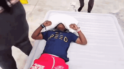 Man In Blue Shirt Laying On Bed With Pillow Over Head GIF