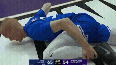 Man In Blue Shirt Laying On Ground During BYU Vs Portland Wrestling Match GIF