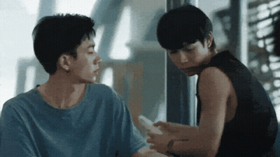 Man In Blue Shirt Looking At Another Man's Phone GIF