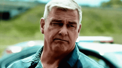 Man In Blue Shirt Looking At Camera By Police Car GIF