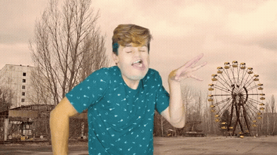Man In Blue Shirt Making Face In Front Of Ferris Wheel GIF