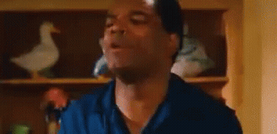 Man In Blue Shirt Making Funny Face With Duck On Shelf GIF