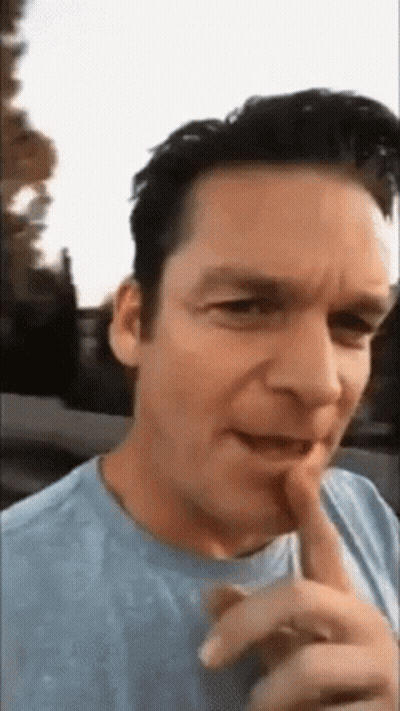 Man In Blue Shirt Making Funny Face With Finger On Lips GIF