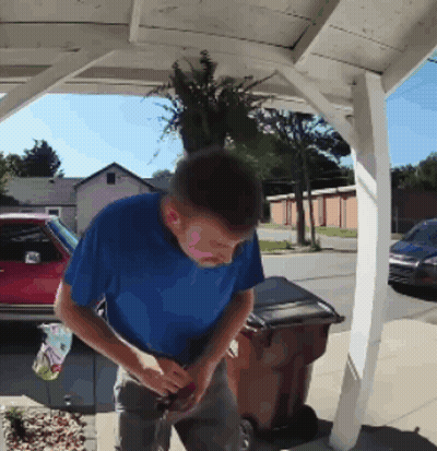 Man In Blue Shirt Next To Brown Trash Can GIF