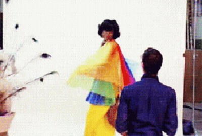 Man In Blue Shirt Next To Woman In Rainbow Dress GIF
