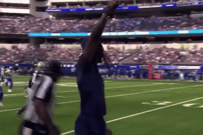 Man In Blue Shirt On Football Field With Arm Up GIF