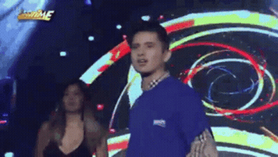 Man In Blue Shirt On Stage With Woman In Black Dress GIF