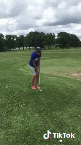 Man In Blue Shirt Putting Golf Ball On Course With TikTok Logo GIF