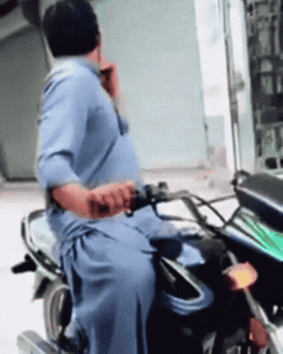 Man In Blue Shirt Riding Motorcycle Talking On Cell Phone GIF