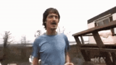 Man In Blue Shirt Running In Front Of Building GIF