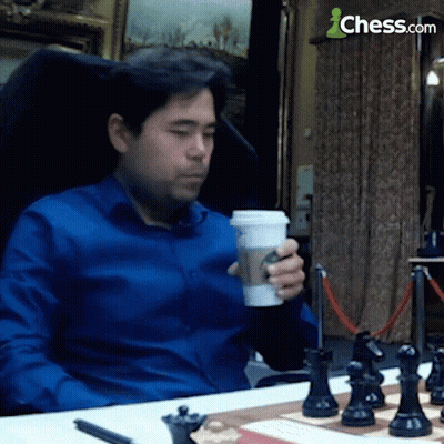 Man In Blue Shirt Sitting At Chess Board With Coffee GIF