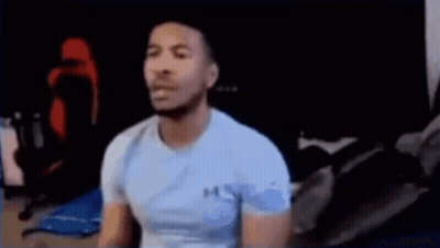 Man In Blue Shirt Sitting At Computer On Bed GIF