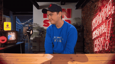 Man In Blue Shirt Sitting At Neon Hey Sign GIF