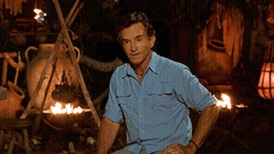 Man In Blue Shirt Sitting By Campfire GIF