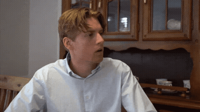 Man In Blue Shirt Sitting By Wooden Cabinet GIF