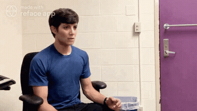 Man In Blue Shirt Sitting In Front Of Purple Door GIF