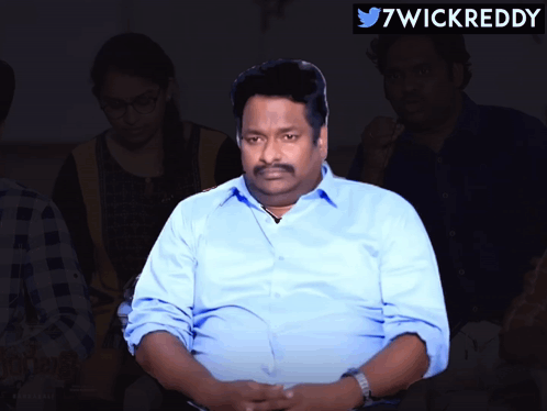 Man In Blue Shirt Sitting In Front Of Twitter Logo GIF