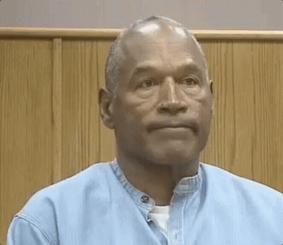 Man In Blue Shirt Sitting In Front Of Wooden Wall GIF